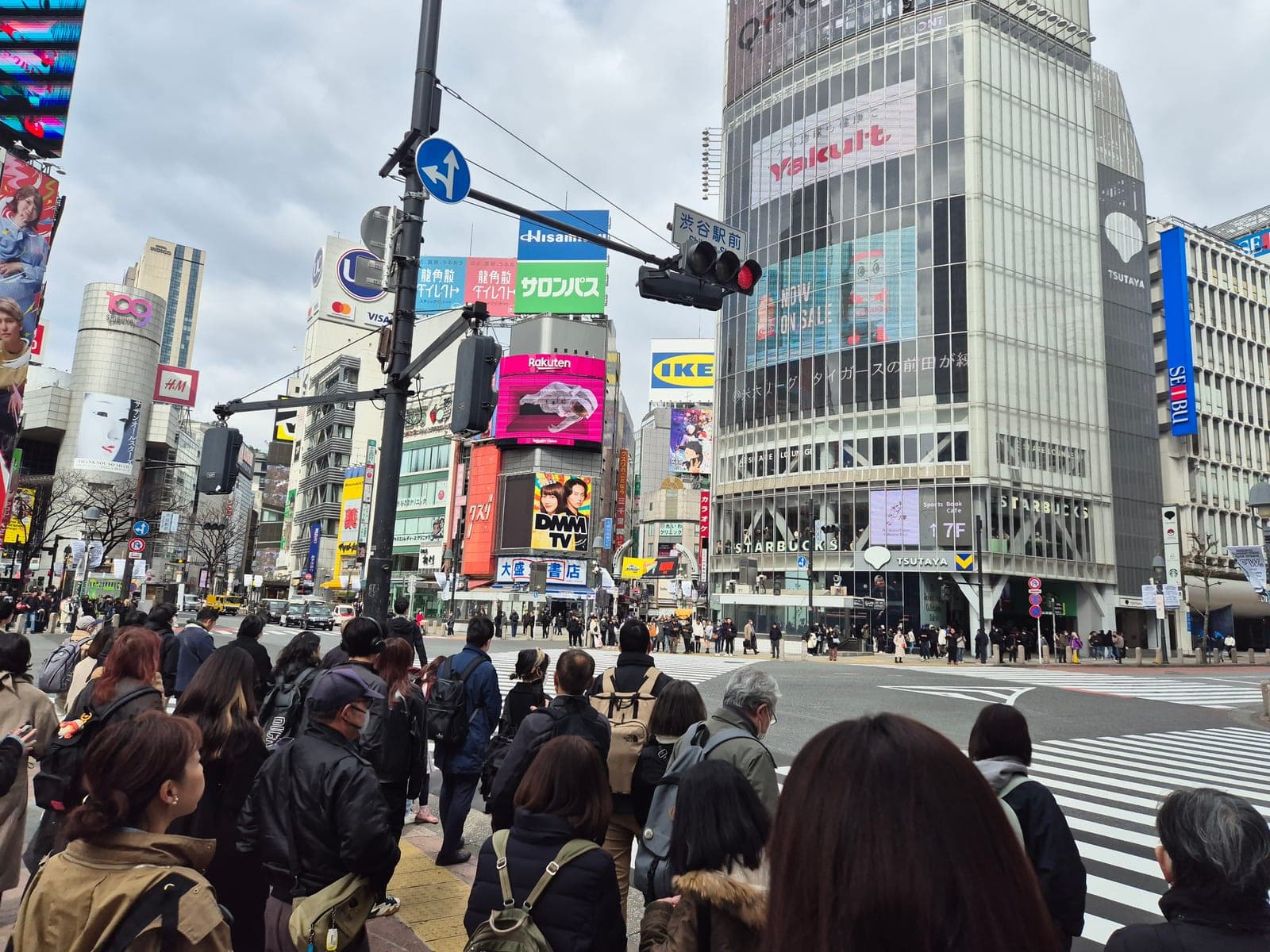 El cruce peatonal de Shibuya en Tokio con multitudes esperando, el edificio Q-Front y sus pantallas gigantes al fondo