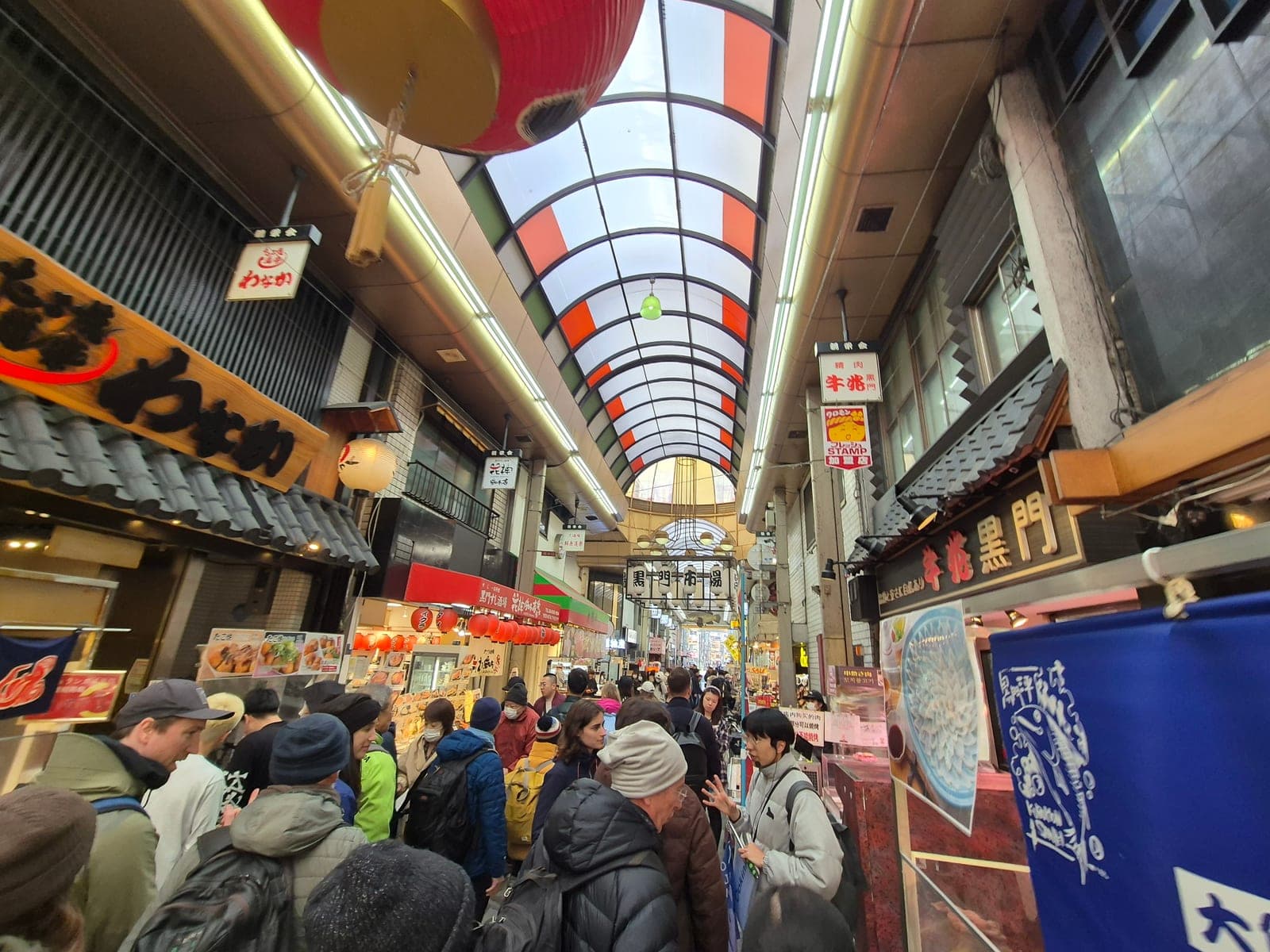 El corredor del mercado Kuromon Ichiba en Osaka lleno de visitantes entre puestos de comida
