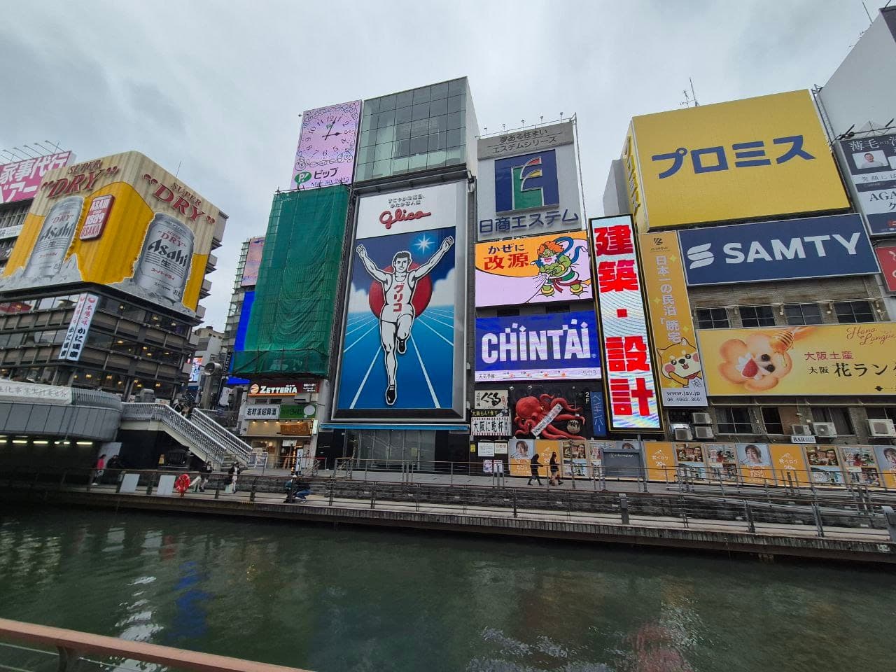 El letrero del corredor Glico y los edificios con anuncios de neón frente al canal de Dotonbori en Osaka